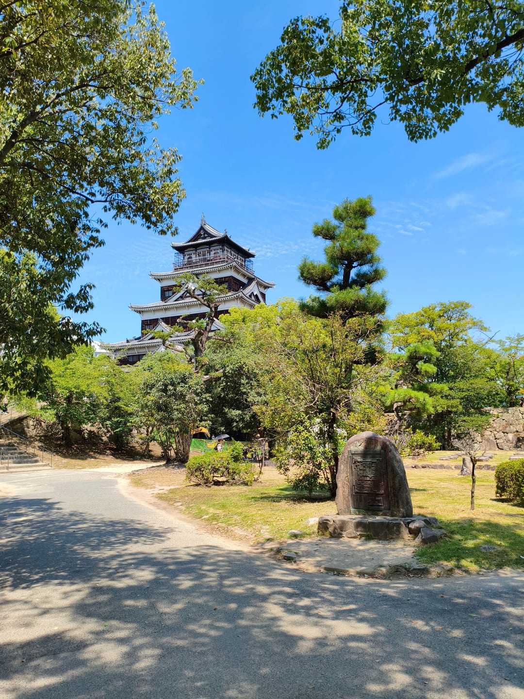 The reconstructed keep of Hiroshima Castle seen across a lawn, with a pine tree beside it