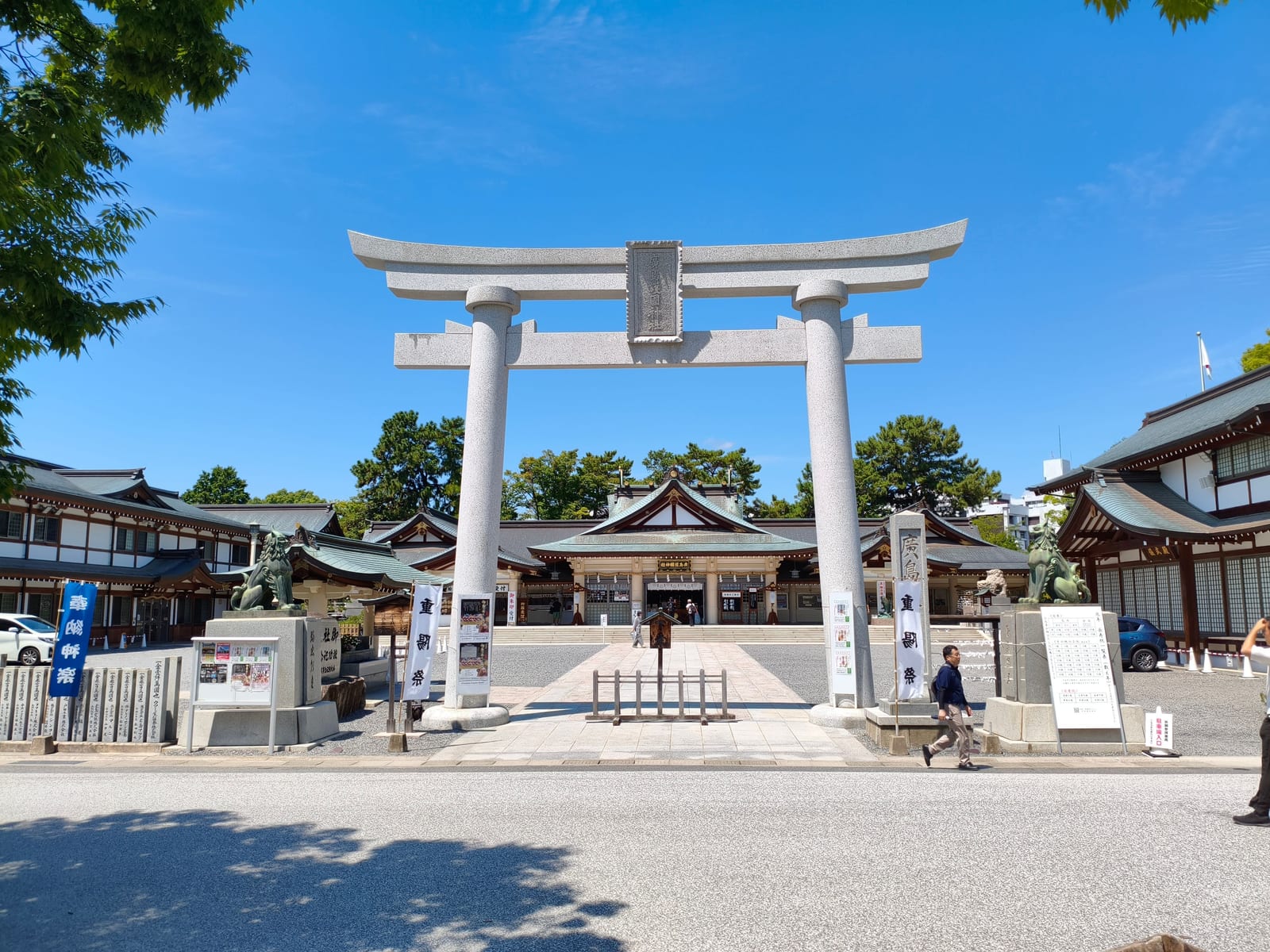 A large stone torii standing in front of shrine buildings under a bright blue sky, inside the castle grounds