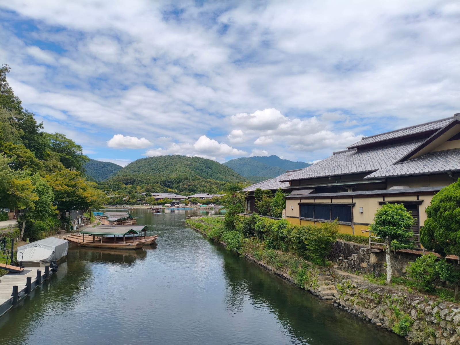 The river at Arashiyama with moored wooden boats and the wooded mountain rising behind