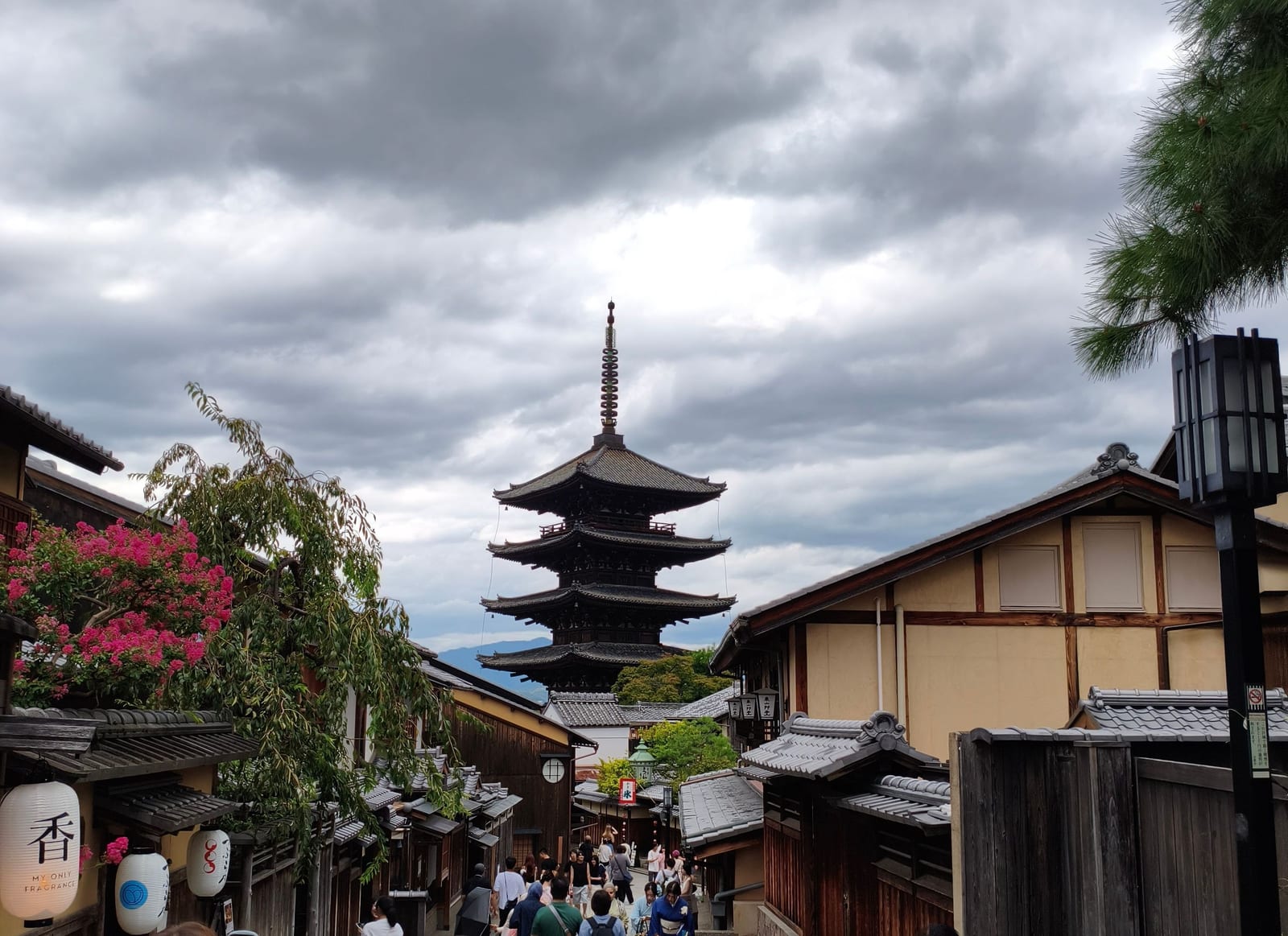 The Yasaka Pagoda rising above the tiled roofs of a sloping stone street in Higashiyama