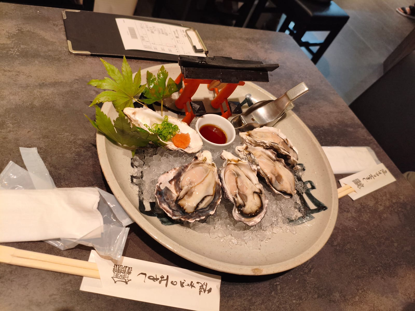 A plate of raw oysters on the half shell served on ice with lemon and a dipping sauce