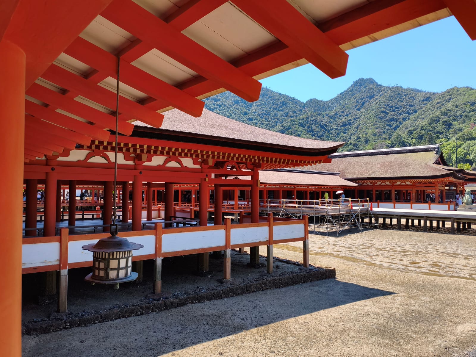 The vermilion corridors of Itsukushima Shrine built out over the water, hills rising beyond