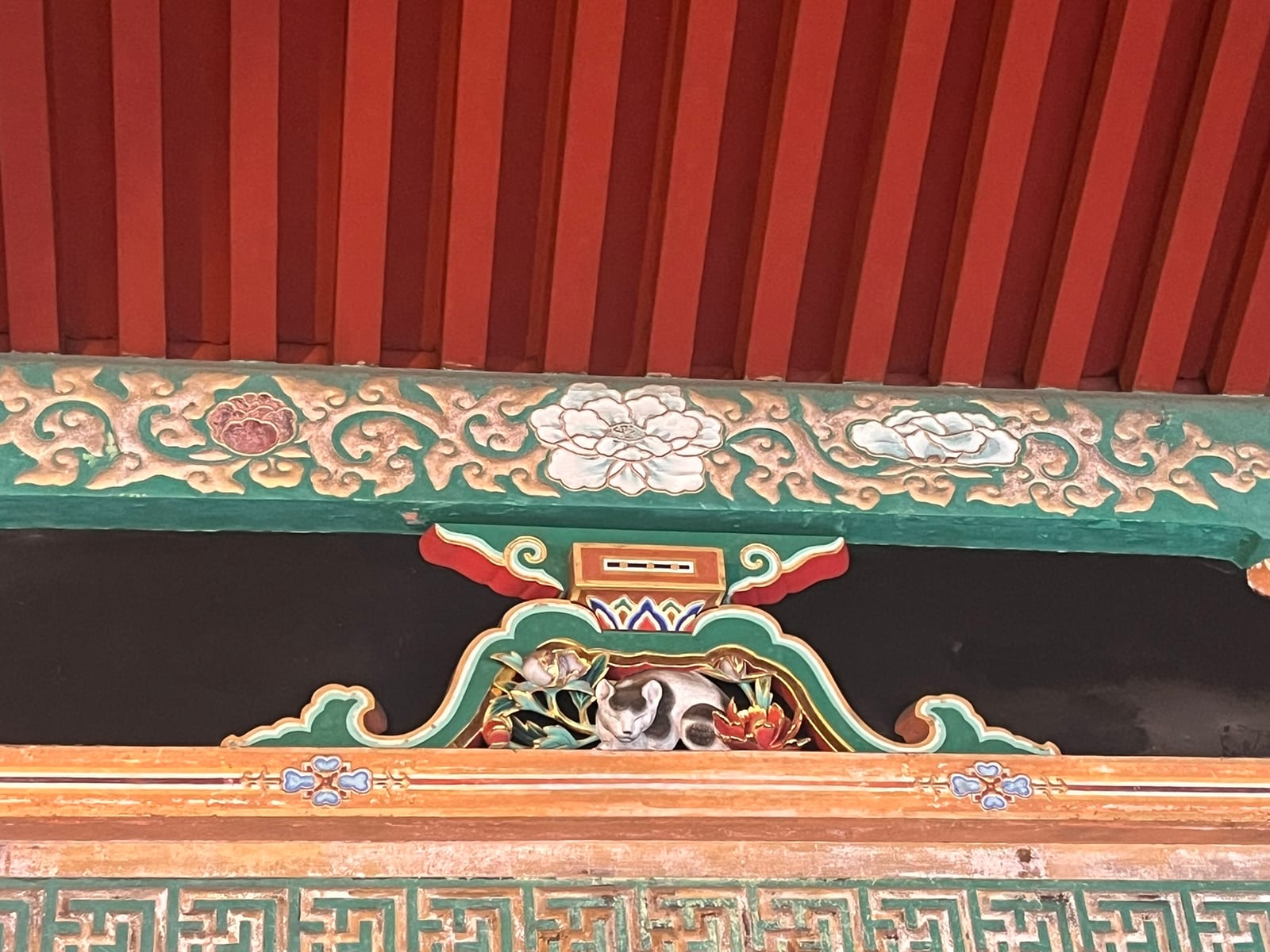 A carved and painted panel of a sleeping cat among peonies above a gateway at Tōshō-gū