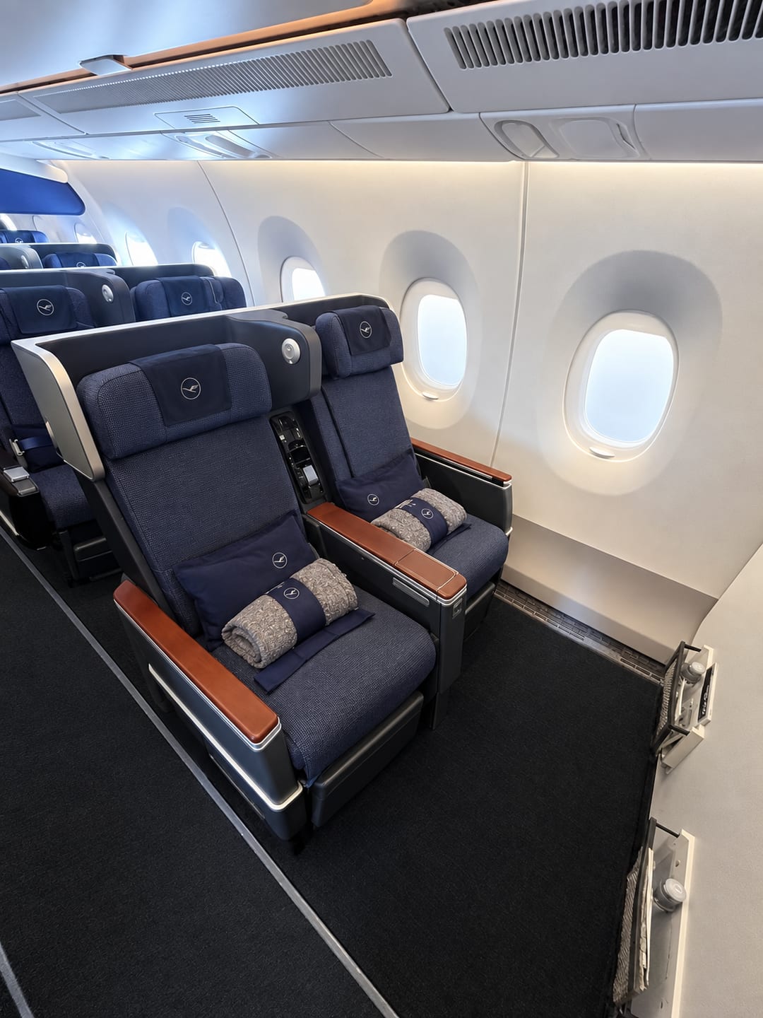 Lufthansa premium economy cabin, two seats by the window with blankets and pillows on them