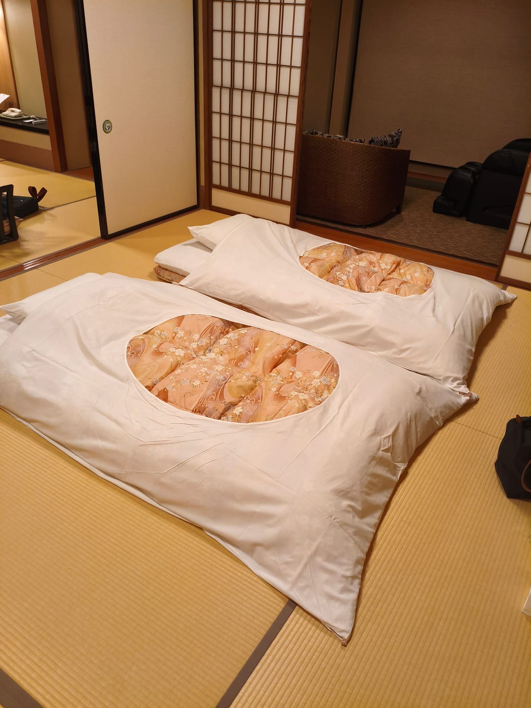 Two futons made up side by side on a tatami floor, laid out while the guests were at dinner