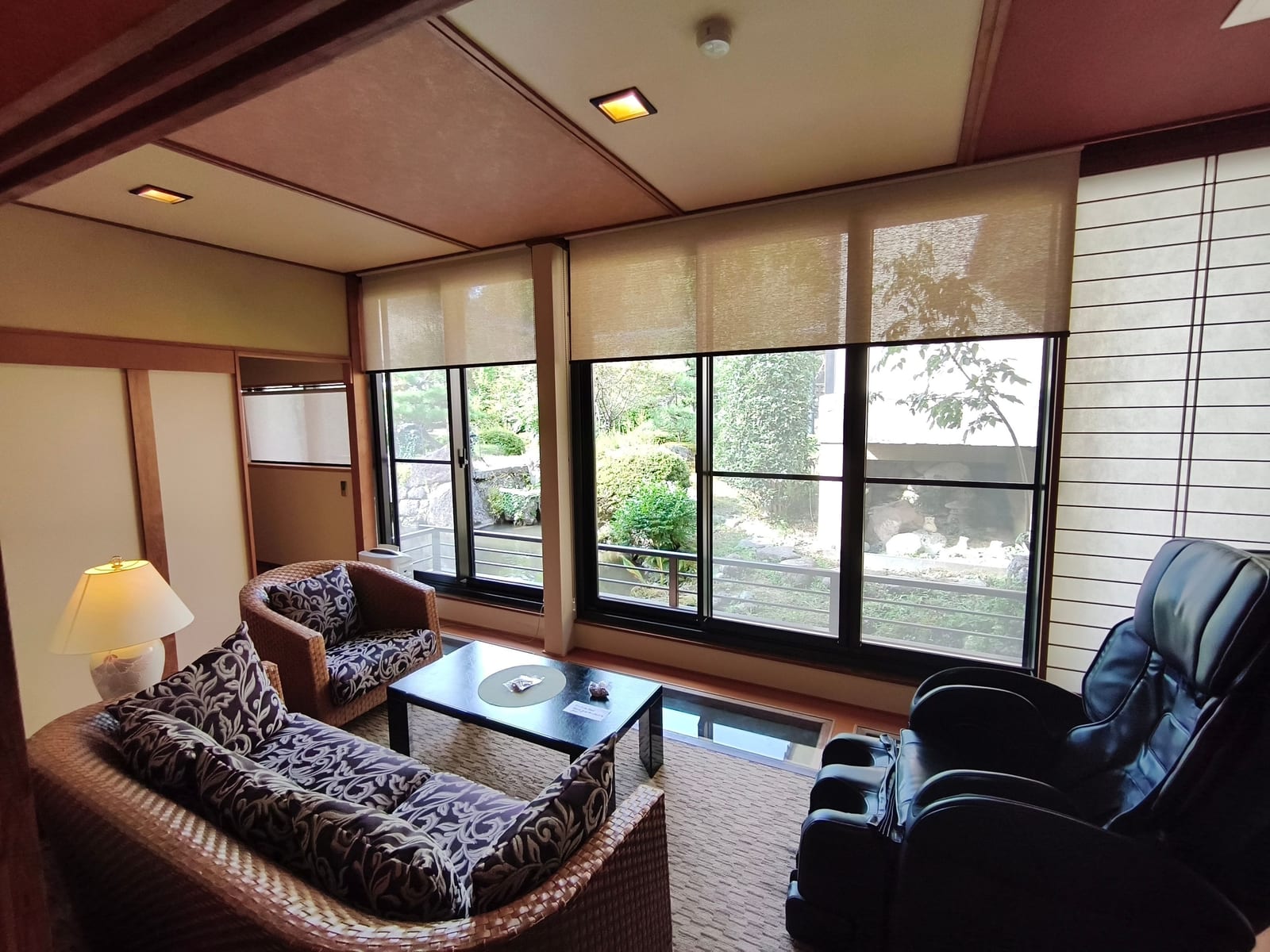 The sitting area of a ryokan room, with armchairs and a low table in front of windows looking onto the garden