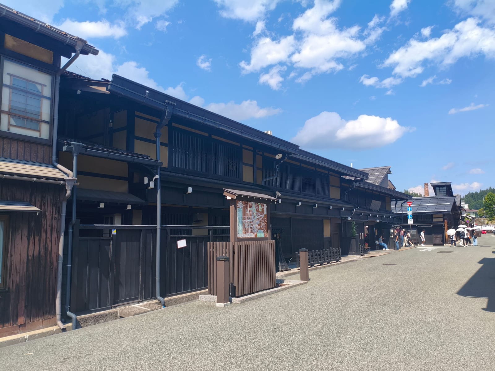 A street of dark wooden Edo-period merchant houses in Takayama old town under a blue sky