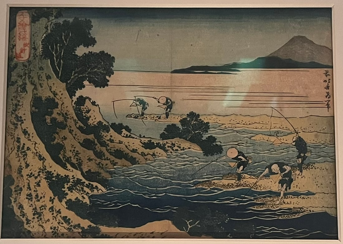 Hokusai woodblock print of fishermen with long rods in a river below a wooded cliff, Mount Fuji on the horizon