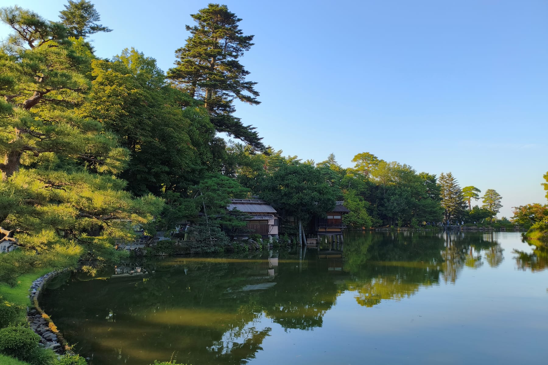Kenrokuen garden in Kanazawa at golden hour, pines reflected in a still pond